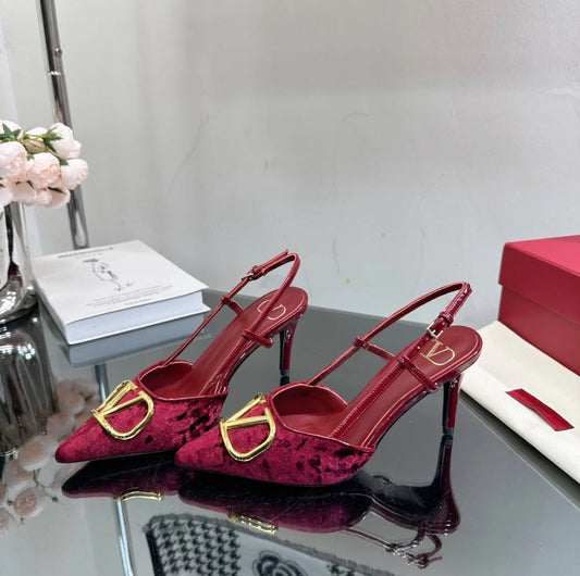 Burgundy red heels with a gold logo on the toe